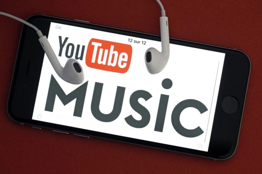 Smartphone com YouTube Music na tela e fones de ouvido sobre ele.