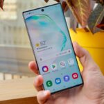 Galaxy Note 10 com a tela ligada sendo segurado na mão.