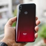 Redmi 7 vermelho sendo segurado por uma mão.