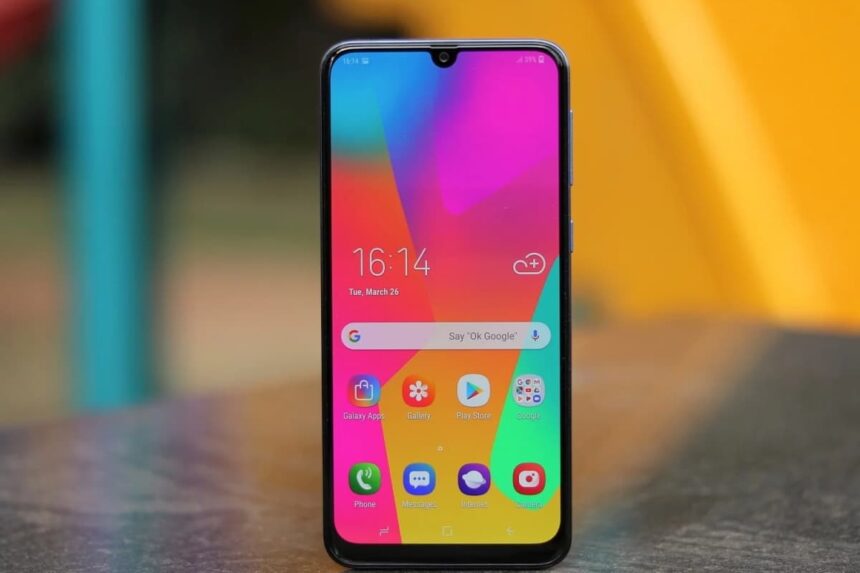 Foto do Samsung Galaxy M30 em pé com a tela ligada.