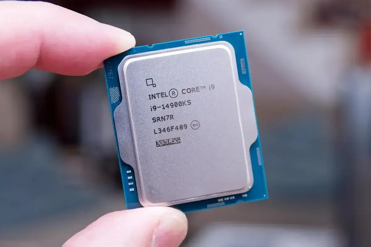 Foto do processador Intel Core i9-14900KS sendo segurado pelas bordas entre os dedos indicador e polegar de uma pessoa.