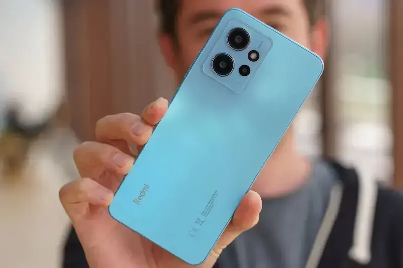 Quais são os melhores smartphones Xiaomi para comprar no momento? Pessoa segurando o Redmi Note 12 na cor azul, o destaque da foto é para a traseira do aparelho.