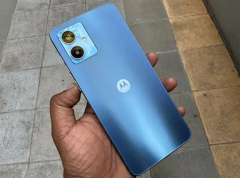 Moto G14 ou Galaxy A14? Saiba qual é o melhor celular de entrada Foto da traseira do Moto G14 sendo segurado por uma mão.